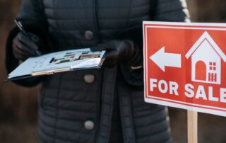 Man in Black Jacket Holding Red and White For Sale Sign || Housing Market